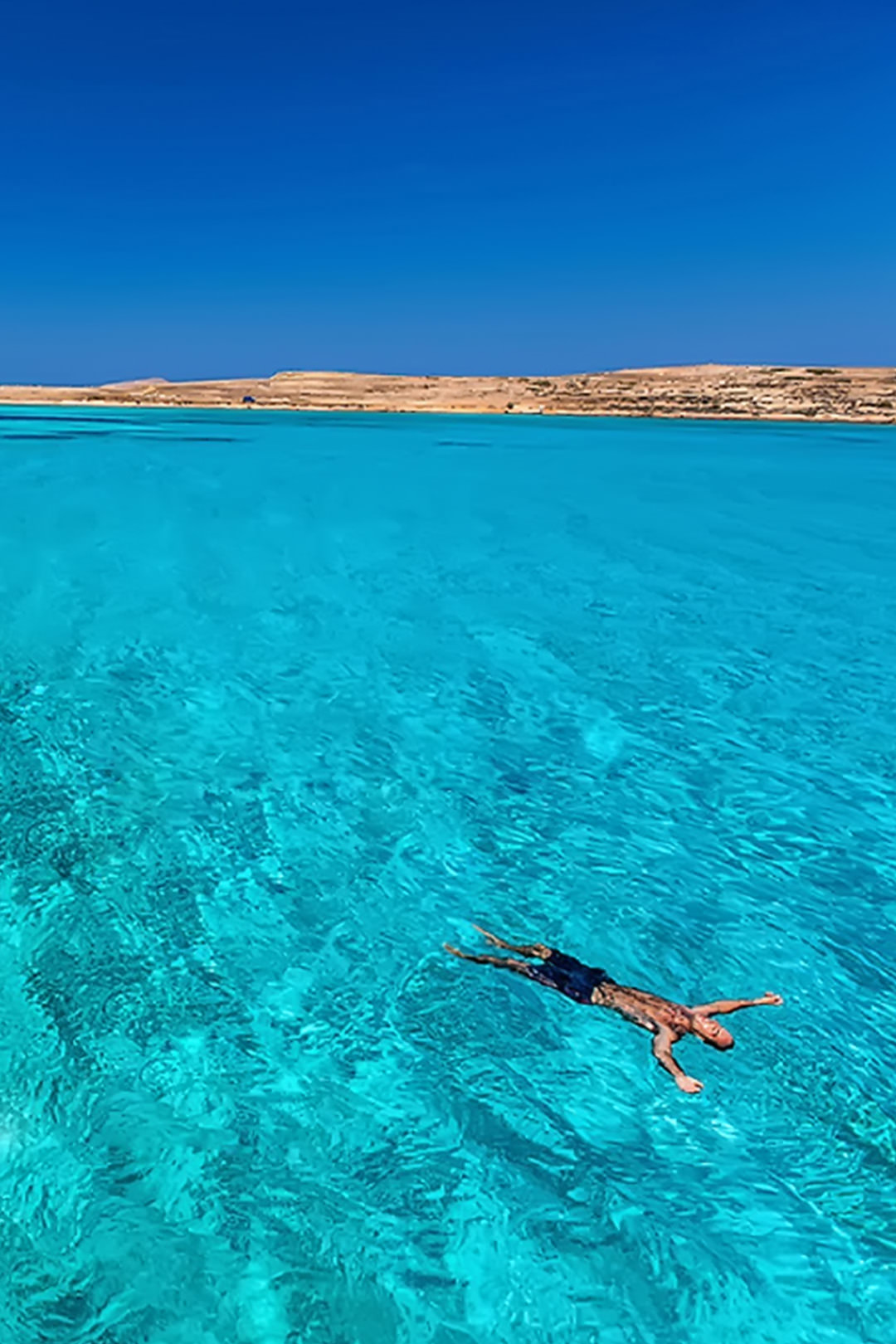 Man floating and enjoying the turquoise waters in Koufonisia, Greece