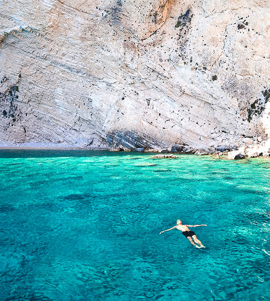 Man swimming into the endless blue of the Aegean sea, Greece