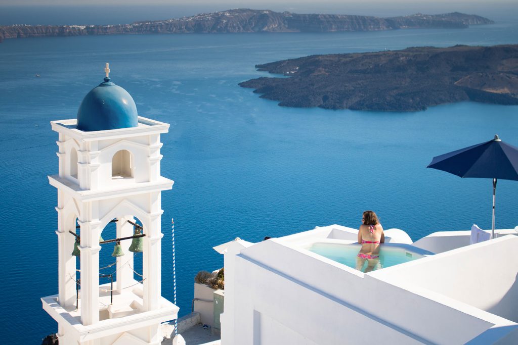 Woman overlooking the Aegean sea from hotel pool in caldera Santorini Woman overlooking the Aegean sea from hotel pool in caldera Santorini